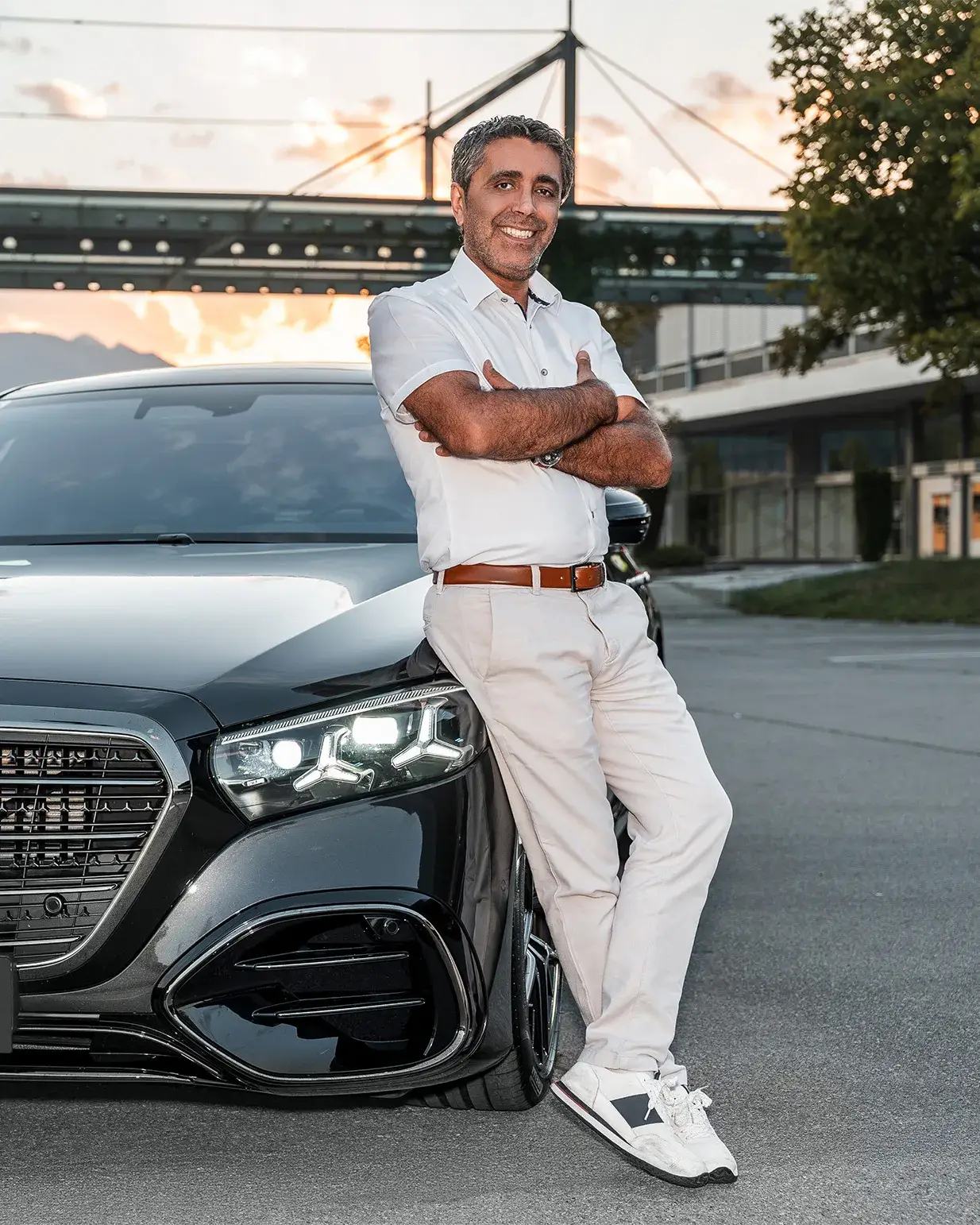 Engin Zengin lehnt mit verschränkten Armen an seiner schwarzen Mercedes S-Klasse