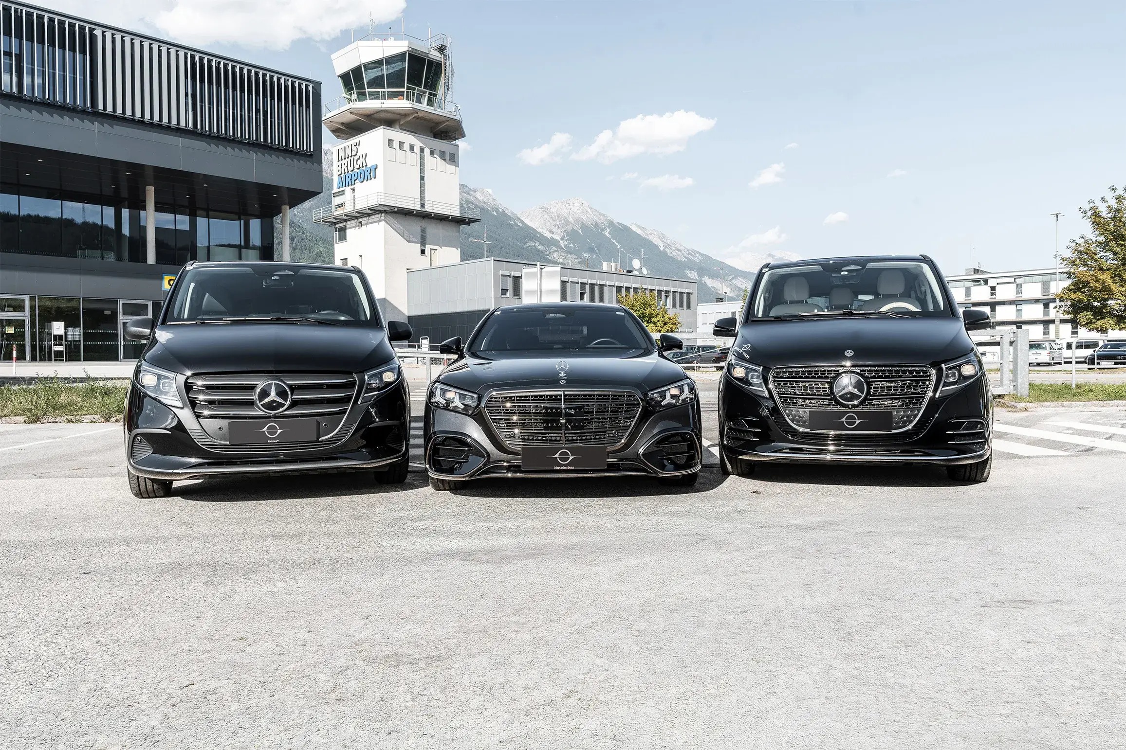 Space Taxi fleet in front of the terminal and tower of Innsbruck Airport, the Nordkette behind