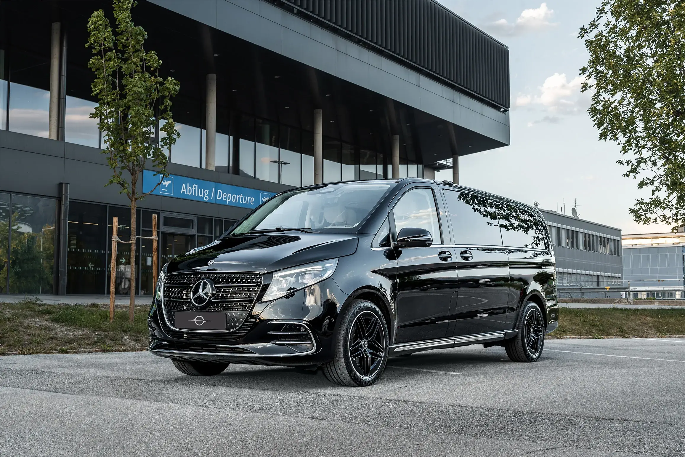 Zwarte Mercedes V-Klasse voor de vertrekhal van de luchthaven Innsbruck